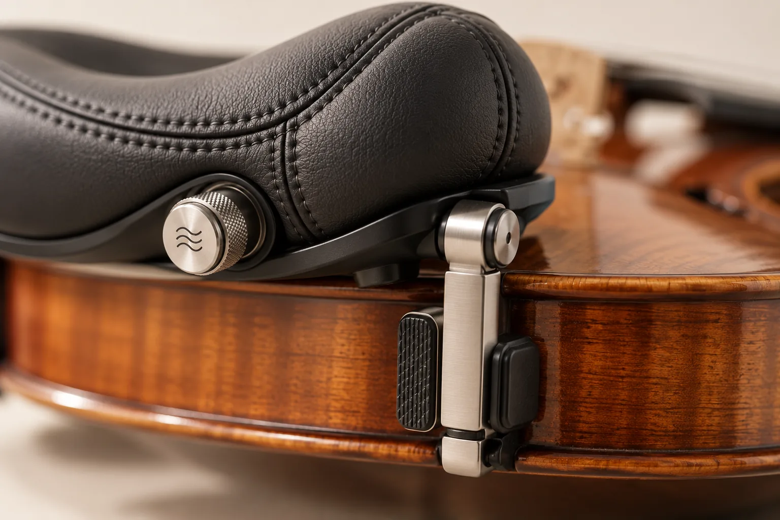 Close view of the pivoting clamp foot and rubber pad against the rib of a violin